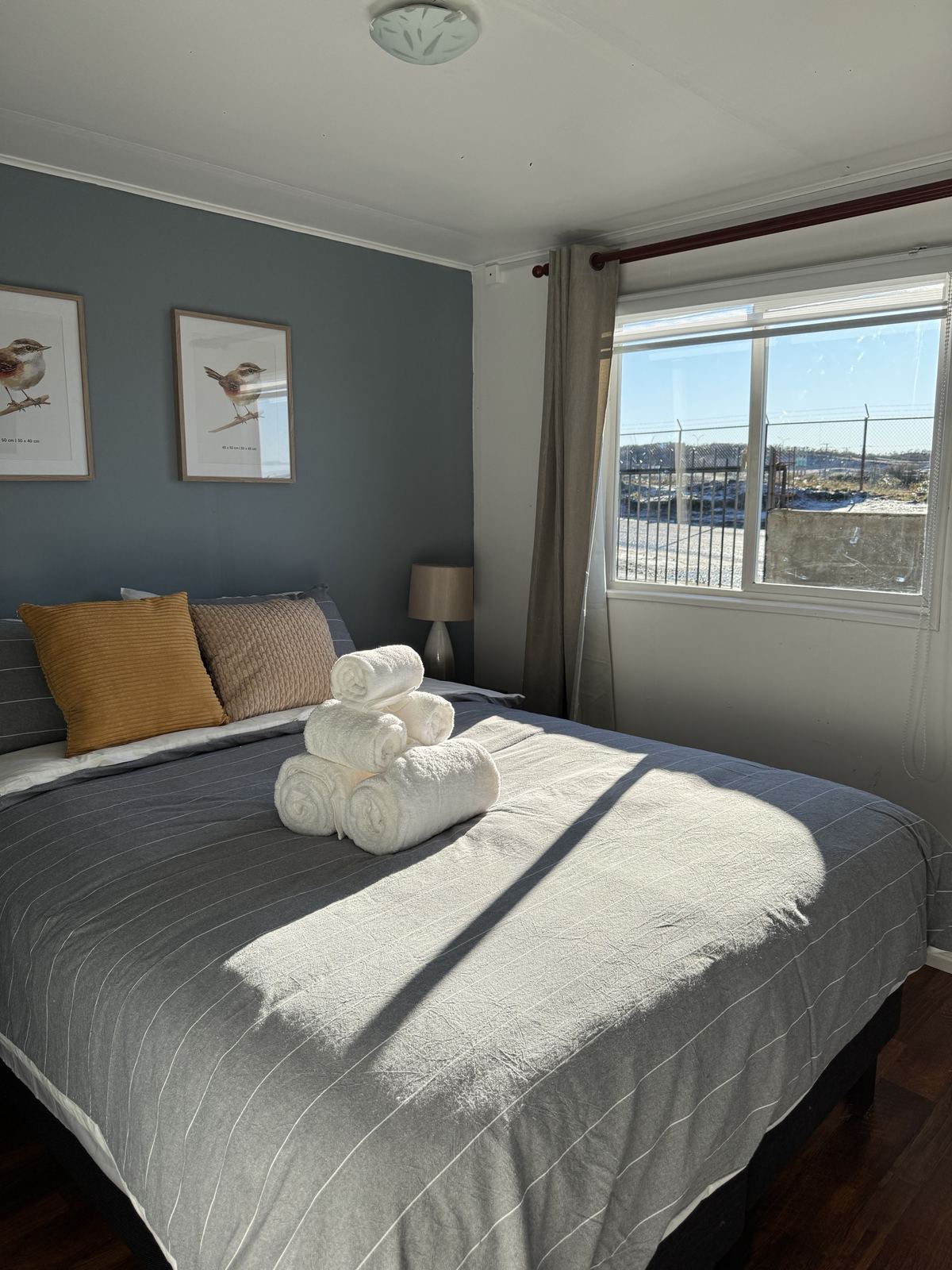 Dormitorio principal con cama de dos plazas, toallas enrolladas y luz de sol