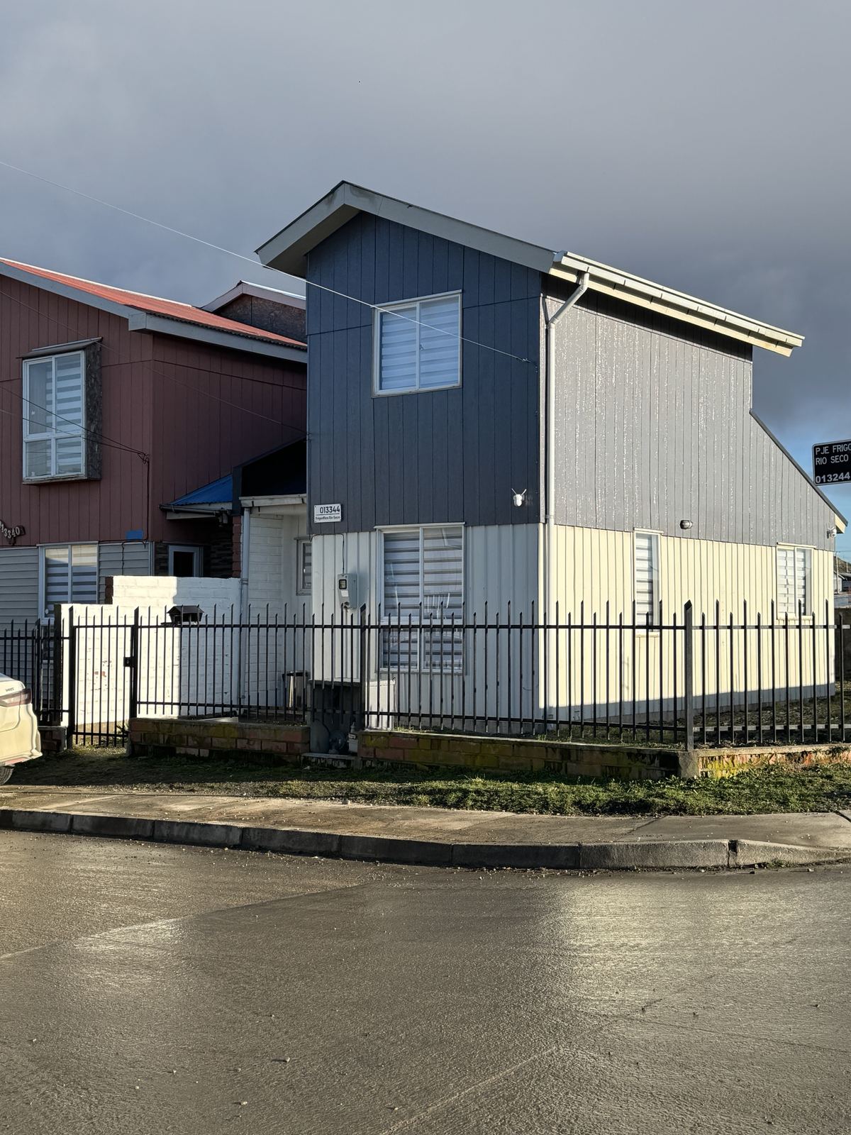 Fachada de Casa Bruma, casa de dos pisos gris y blanca con reja negra